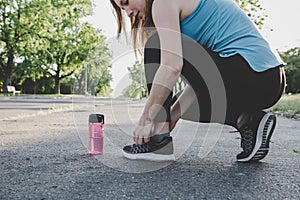 Preparing for running. Young woman tying her running shoes in the park