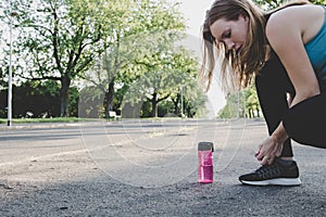 Preparing for running. Young woman tying her running shoes in the park