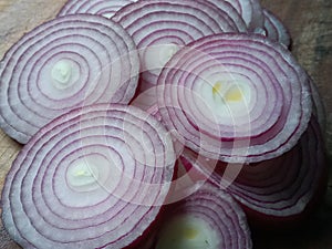 Freshly thin sliced red onions on a wooden chopping board