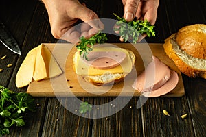 Preparing a sandwich in a restaurant on the kitchen table. The chef hand adds fresh parsley to the sandwich. Advertising space