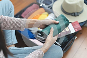 Preparing suitcase for vacation trip. Young woman checking accessories and stuff in luggage on the bed at home before