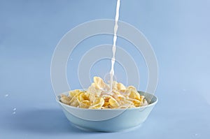 Preparing tasty sweet corn flakes with milk.Bowl full of cornflakes, pouring milk into the bowl