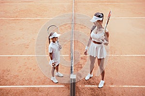 Preparing to big game! Full length top view of a smiling female tennis coach teaching child at clay court before game. Tennis