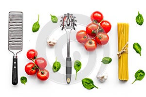 Preparing to cook pasta. Spaghetti, tomatoes, garlic, cheese grater, spoon for spaghetti on white background top view