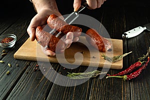 Preparing to grill sausages. Stringing Munich sausages on a fork by the hands of a cook on the kitchen table. Space for recipe or