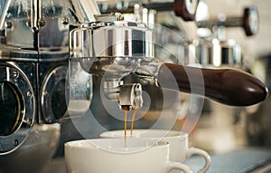 Preparing to perfection. Small cups to serve hot coffee drinks. Coffee cups. Coffee being brewed in coffeehouse or cafe photo