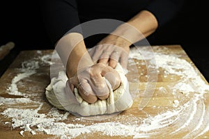 Woman hands kneading fresh dough for making bread or pizza.