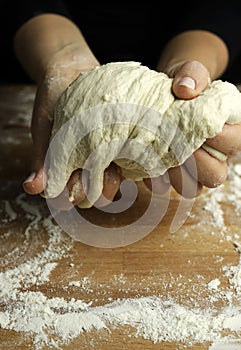 Woman hands kneading fresh dough for making bread or pizza.