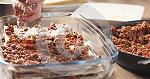Preparing traditional italian lasagna adding cheese