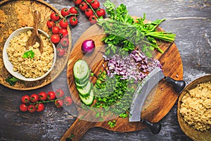 Preparing traditional oriental salad Tabouleh with couscous or bulgur, ingredients on cutting board