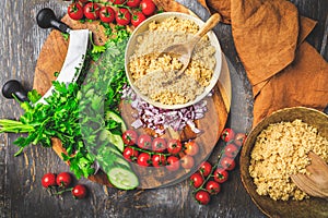 Preparing traditional oriental salad Tabouleh with couscous or bulgur, ingredients on cutting board