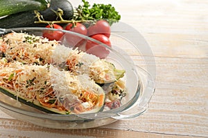 Preparing a vegetarian low carb diet meal from zucchini filled with vegetables, feta cheese and parmesan in an ovenproof glass