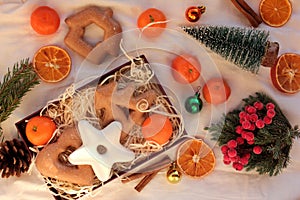 Preparing winter holidays gift box. Flat lay composition with Christmas gingerbread cookies, citrus fruits, ornaments