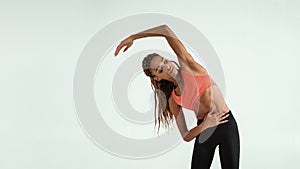 Preparing for workout. Beautiful young african woman in sportswear doing stretching exercises while standing against