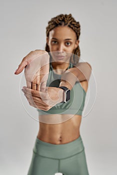 Preparing workout. Vertical shot of a young beautiful mixed race woman in sportswear stretching her arms while standing