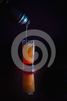 Prepartion of the sunrise cocktail with red grenadine juice, whiskey, and lemon syrup