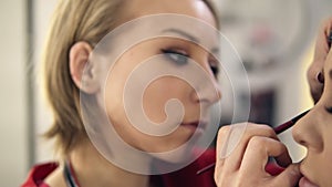 Prepation process of gourgeous young woman. Hairdresser is twisting long fair hair with a culring rod and make-up artist