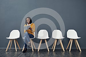 Prepping for her interview. Full length shot of an attractive young woman using her laptop while waiting in line for a