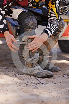 Prepping before the race. a dirt bike rider putting on his protective boots.