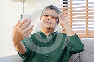 Presbyopia, Hyperopia mature asian woman holding eyeglasses having problem with vision problem trying to read text on mobile, eye