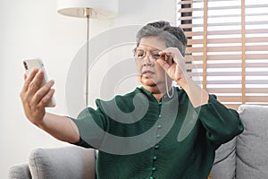 Presbyopia, Hyperopia mature asian woman holding eyeglasses having problem with vision problem trying to read text on mobile, eye