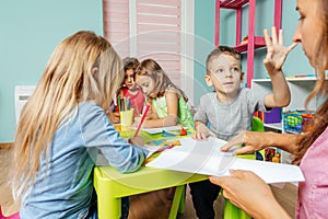 Preschool boy demands teacher's attention during art lesson