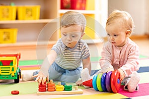 Preschool boy and girl playing on floor with educational toys. Children at home or daycare.