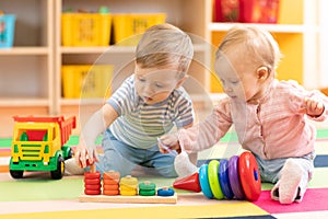 Preschool boy and girl playing on floor with educational toys. Children at home or daycare.