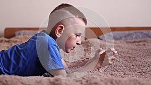 Preschool boy at Home is Lying on the bed, using a Smartphone. Child playing video games on a cellphone, Browses
