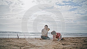 Preschool boy playing beach with young mother. Happy parent kid resting together