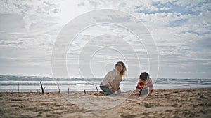 Preschool boy playing beach with young mother. Happy parent kid resting together