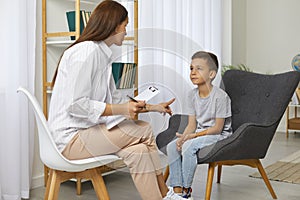 Preschool boy practicing sounds articulation during lesson with speech language therapist teacher.