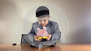 Preschool boy in a suit trying to get more money from an empty piggy bank. Recession and negative returns on investment