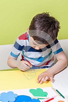 A preschool boy use a pencil for homework received from kindergarten