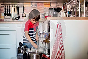 Preschool child, boy, helping mom, putting dirty dishes in dishwasher