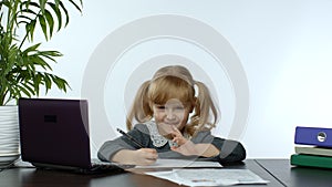 Preschool child girl distance online learning at home. Kid studying using digital laptop computer