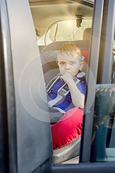 Preschool cute 3-4 years old boy sitting in safety car seat and crying during family travel by car  bad mood  negative emotion 