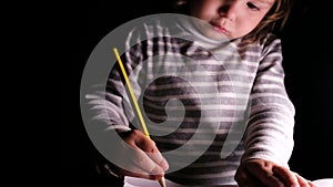 Preschool girl draws a pencil on a sheet of paper, close-up