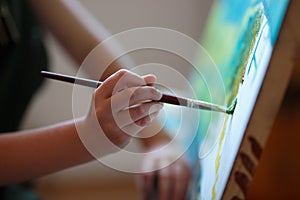 Preschool girl painting in art class. Close up photo brush in hand