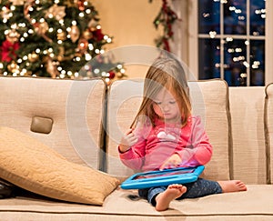 Preschool girl using a tablet computer at home at Christmas