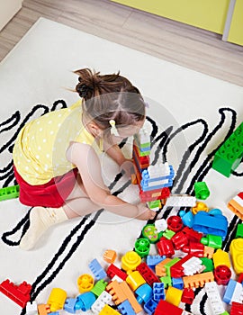 Preschool girl who build towers with plastic cubes