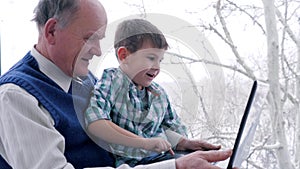 Preschool home education, old man with child with laptop in hand indoors