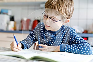 Preschool kid boy at home making homework writing letters with colorful pens
