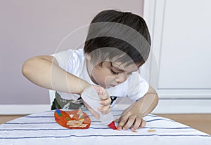 Preschool kid putting glue stick on paper for his school homework, Cute little boy using colour paper making easter eggs for DIY