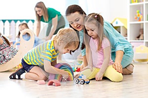 Preschool kids playing with building bricks in while sitting on floor in daycare