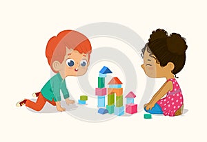 Preschool Red Hair Boy and African American Girl Kids playing with wooden bricks and blocks together in kindergarten