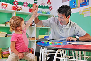 Preschool teacher and child giving high-five photo