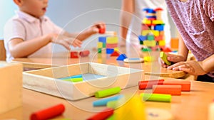 Preschool teacher with children playing with colorful didactic toys at kindergarten