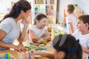 Preschool teacher with children playing with colorful didactic toys at kindergarten