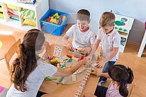 Preschool teacher with children playing with colorful didactic toys at kindergarten